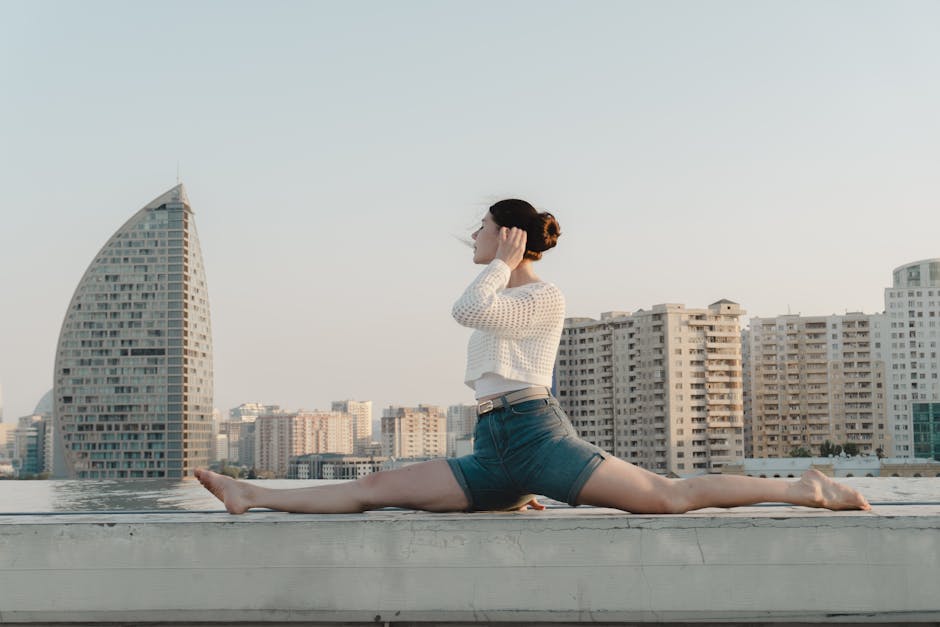 Woman in a white top performing a yoga pose on a paddleboard at sunset